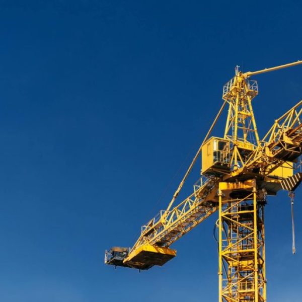 construction-crane-tower-in-sun-light-beams-on-background-of-blue-sky-768x512